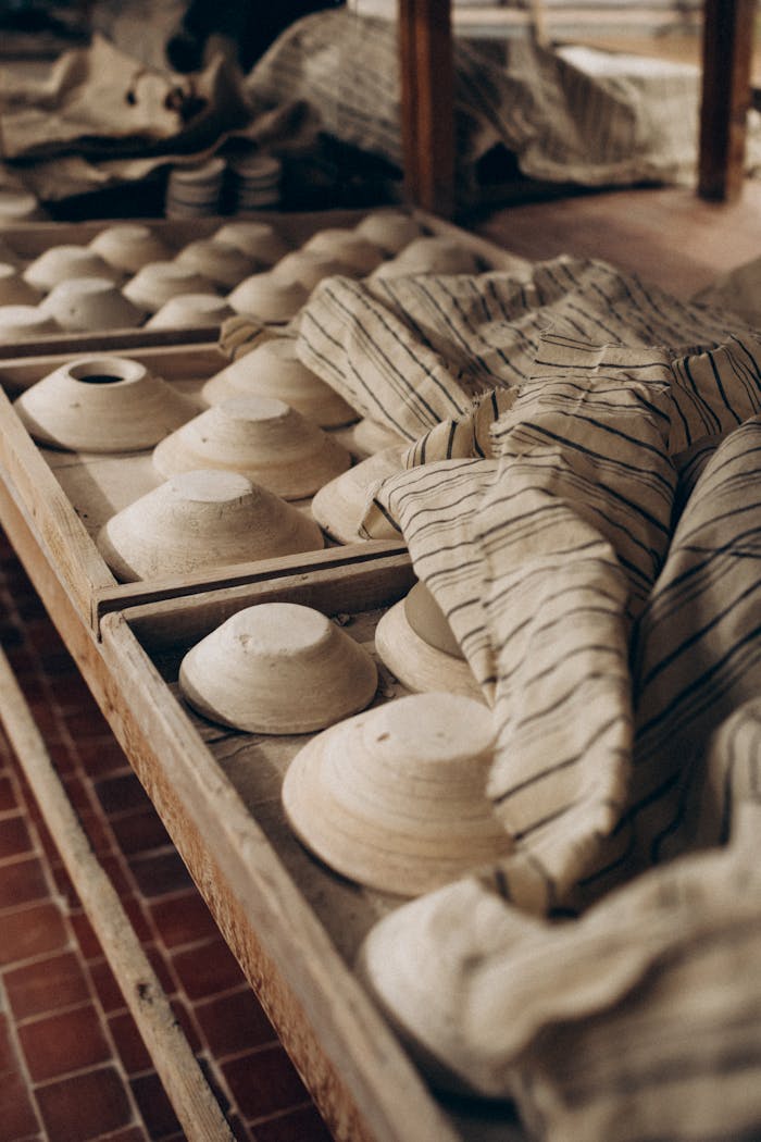 Handcrafted clay pottery drying in a rustic artisan workshop setting.