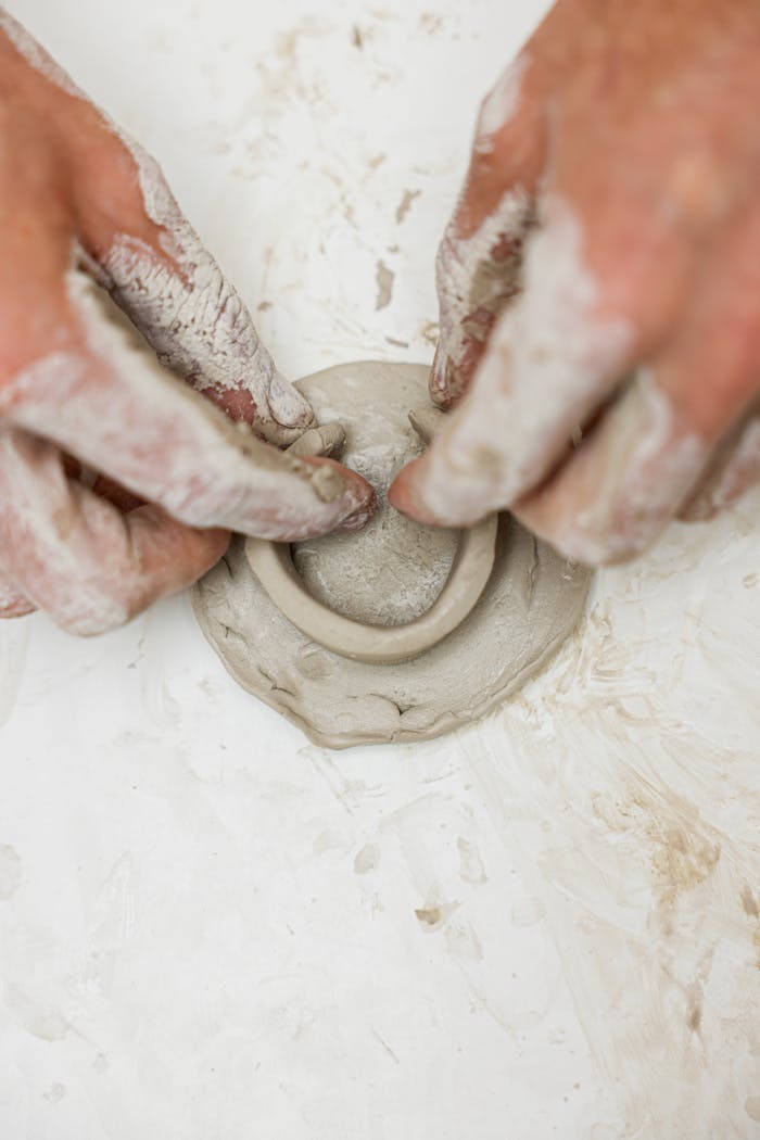 Hands molding clay in a detailed artistic process, highlighting craftsmanship.